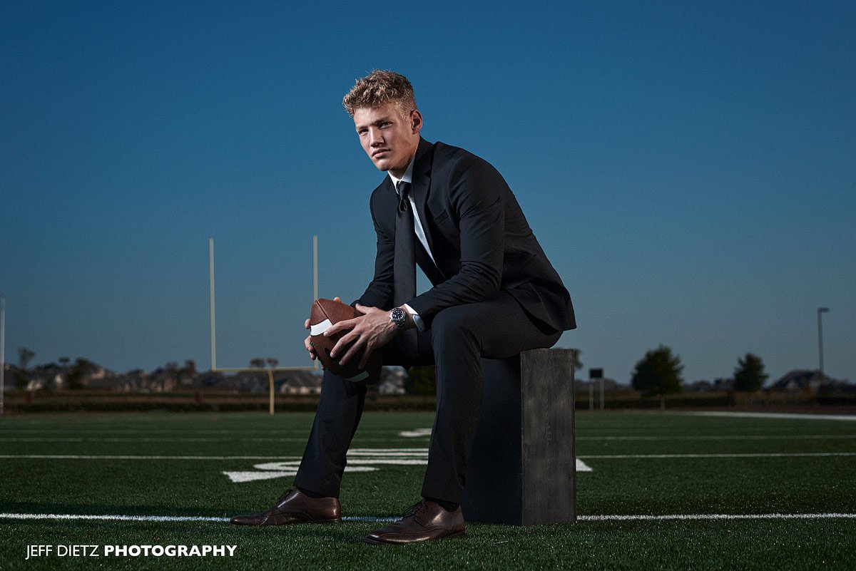 Prosper senior photos of football player on high school field in suit