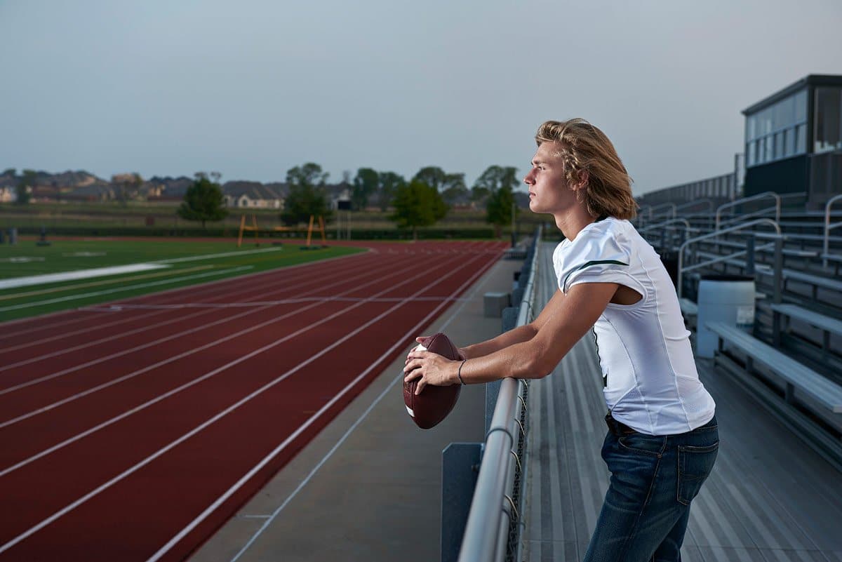 prosper high school senior looking over the field in his jersey for senior pictures