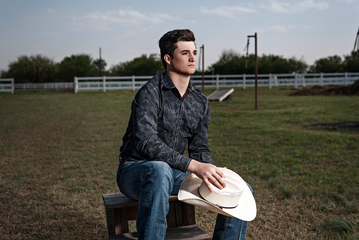 prosper senior guy photos with cowboy hat sitting at horse farm