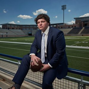 nick trice sitting on ledge at allen football stadium for high school sports photos