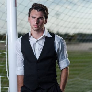photos of soccer player by a goal in a vest for senior portraits