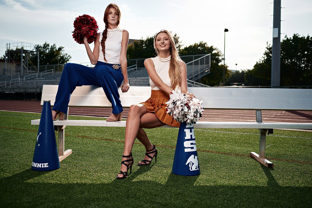 2 dallas cheerleaders friends pose for senior portraits on a bench at Allen ISD